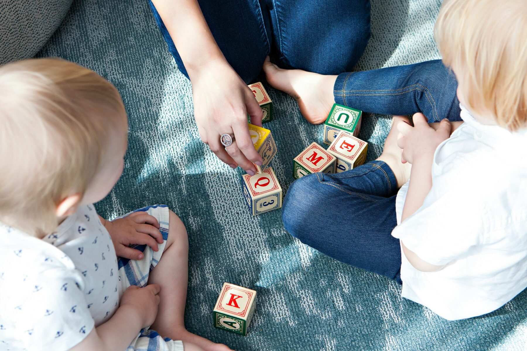 Two children and an adult playing with blocks.