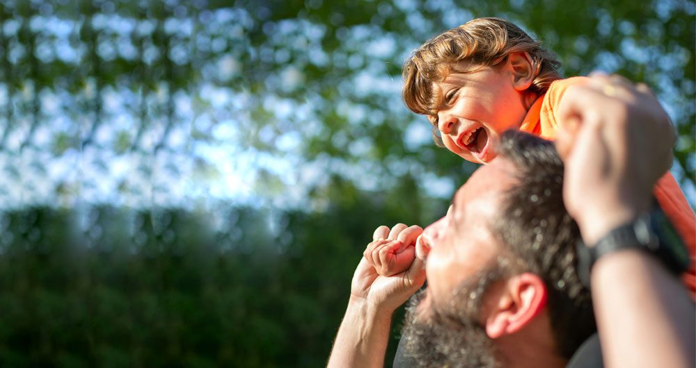 Father carrying a laughing little boy on his shoulders