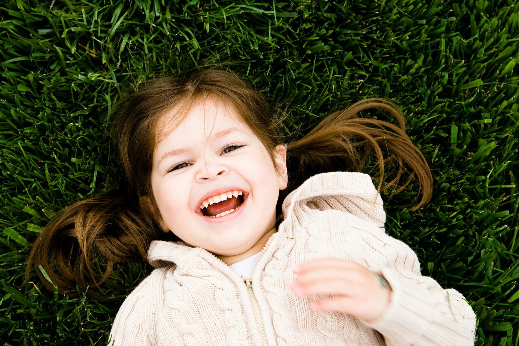 A young girl smiling laying in grass.