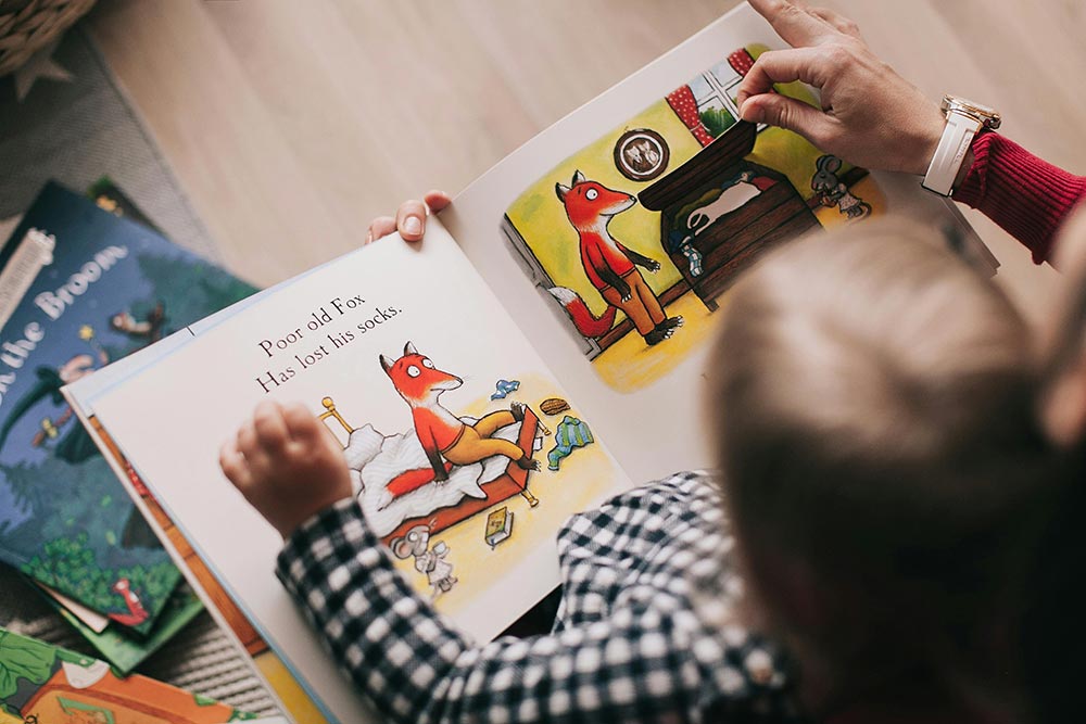 Overhead view of a child being read to sitting in someone’s lap